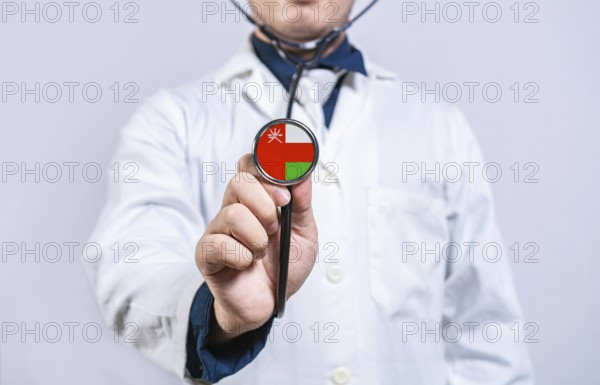 Doctor hands holding stethoscope with Oman flag. Oman health and care concept