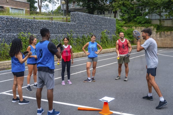 Baseball coach explaining game strategy to team players during training on an outdoor court,