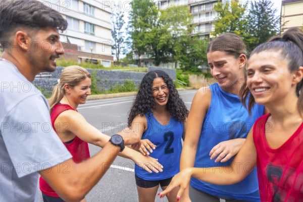 Mixed basketball team celebrating victory after match, putting their hands together, expressing joy