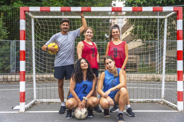 Five a side soccer team posing confidently with soccer balls in front of the goal, embodying