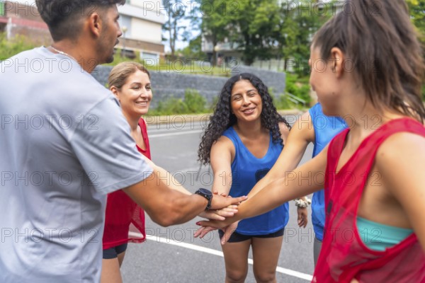 Five smiling soccer players are joining hands before a match, showing their team spirit and
