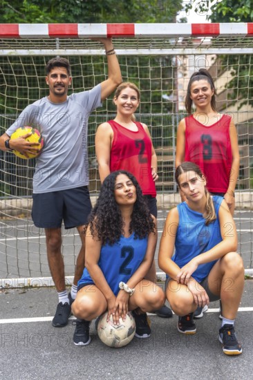 Five young soccer players, wearing numbered jerseys, are posing for a team photo on an outdoor