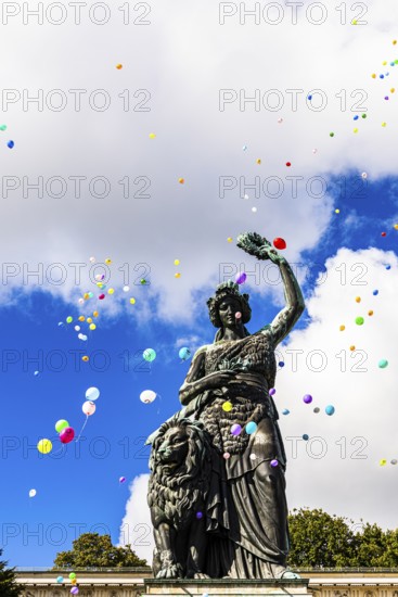 Colourful balloons rise high above the statue of Bavaria into the white-blue sky, grand finale of