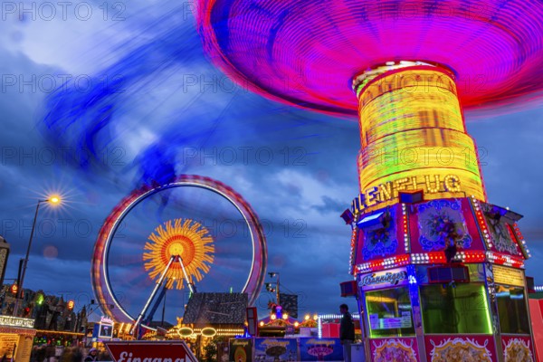Illuminated chain carousel in motion, behind the Ferris wheel in motion, Festwiese, Theresienwiese,
