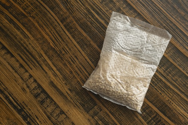 A sachet containing pearl barley is placed on a wooden kitchen table. It is ready for cooking,