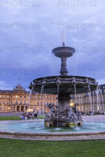 Evening atmosphere at Schlossplatz Stuttgart. View of the New Palace. Illuminated fountain bowl at