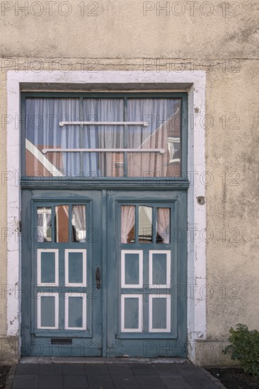 Blue wooden door with windows and white curtains on a rustic building, Old Town Burgsteinfurt,