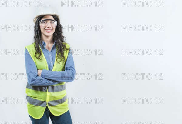 Portrait of smiling female engineer with arms crossed isolated. Young female engineer with helmet