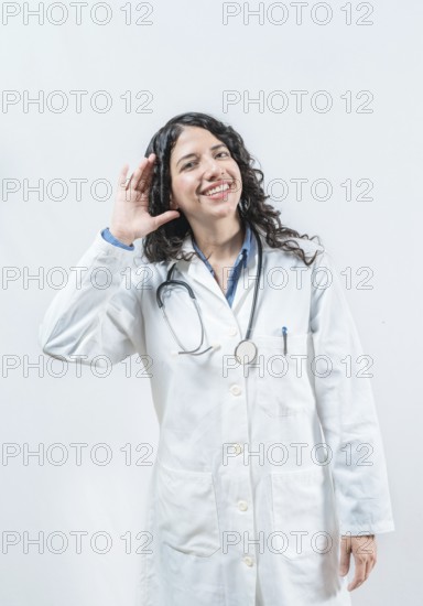 Doctor with hand on ear listening to a rumor, isolated. Latin female doctor hearing a rumor,