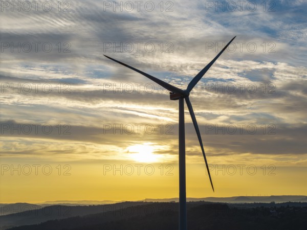A single wind turbine stands majestically against a breathtaking sky at sunrise, near Schorndorf,