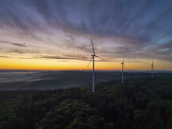 Three wind turbines on a green hill at sunrise with sweeping mountain views, near Schorndorf,