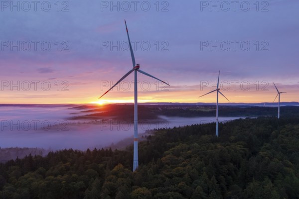 Wind turbines on a hill with sunlight breaking through the fog, sunrise, near Schorndorf, Remstal,