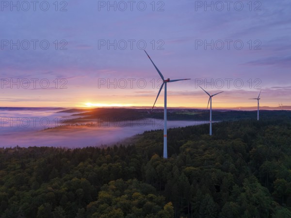 Wind turbines above a colourful forest landscape at dawn, sunrise, near Schorndorf, Remstal,