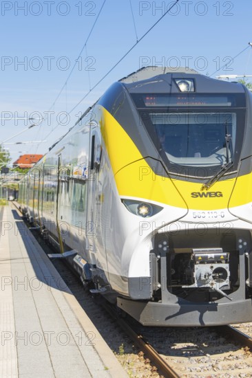 Modern white and yellow train on the track in sunny weather, taken from the side, battery Electric