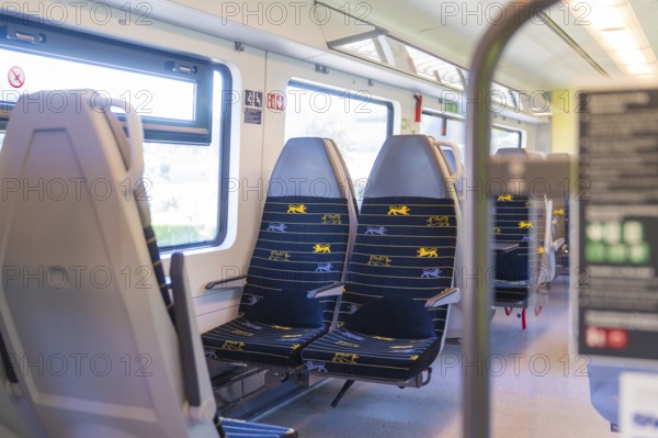 Rows of blue and yellow seats in a clean train compartment, battery Electric train with green