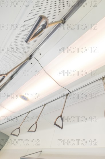 Ceiling view with lighting and grab handles in a modern vehicle, battery Electric train with green