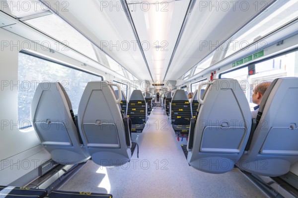 Spacious and modern train compartments with rows of window seats, battery Electric train with green