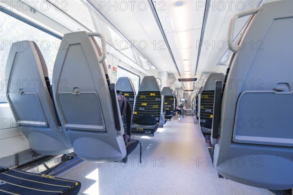 Modern train interior with rows of seats along large windows, battery Electric train with green