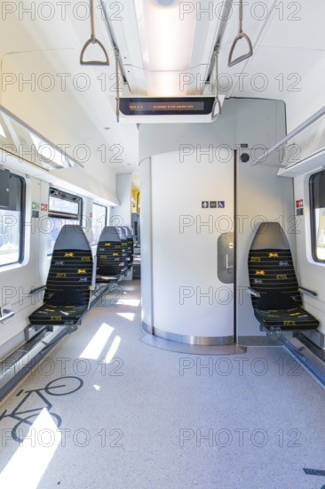 Modern and clean interior of a train with blue rows of seats and lots of light, battery Electric
