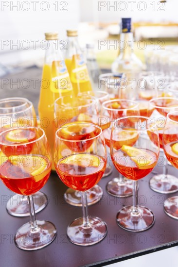 Several cocktail glasses with orange-coloured drink and orange slices, arranged on a table