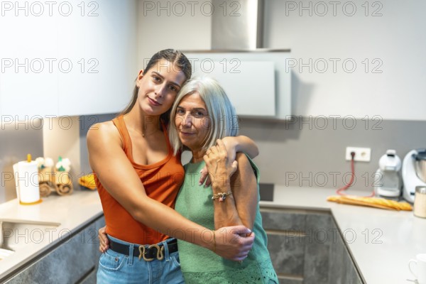 Young woman and senior woman hugging in contemporary kitchen, expressing affection and familial