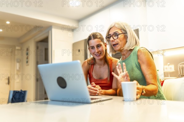 Senior and young women using laptop for a video conference with family, waving and smiling in