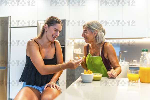 Grandmother and granddaughter laughing together while having a snack of french fries and guacamole