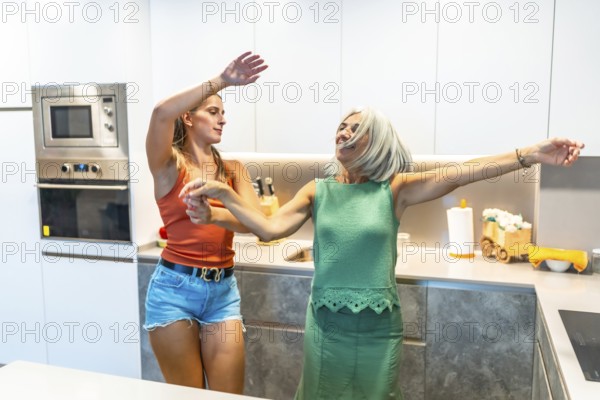 Two women enjoying a lively dance in a sleek, modern kitchen, expressing happiness and energy in a