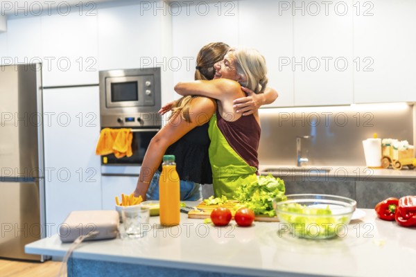 Two women embracing in a kitchen while preparing a vibrant, healthy meal filled with fresh