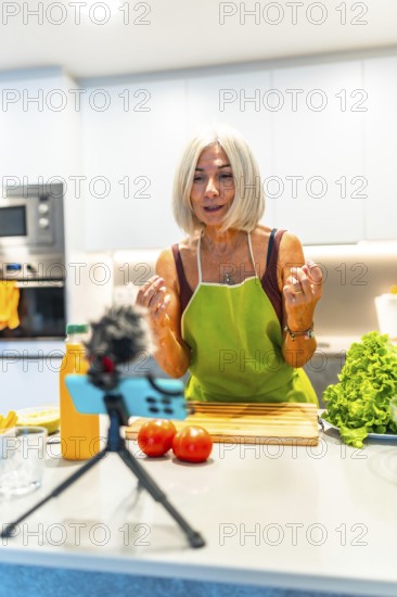 Cheerful mature food blogger engaging with her audience while recording a video tutorial on