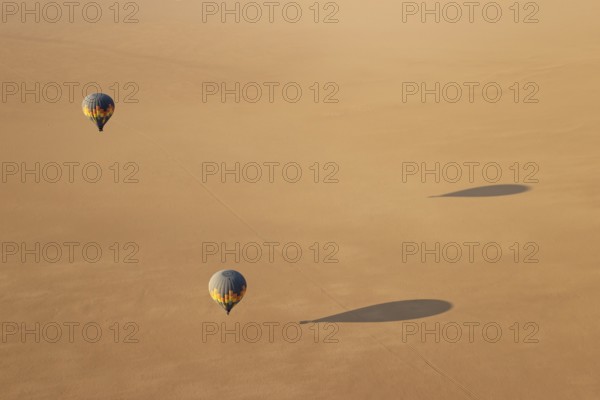 Two hot-air balloons above an arid plain at the edge of the Namib Desert. Aerial view from another