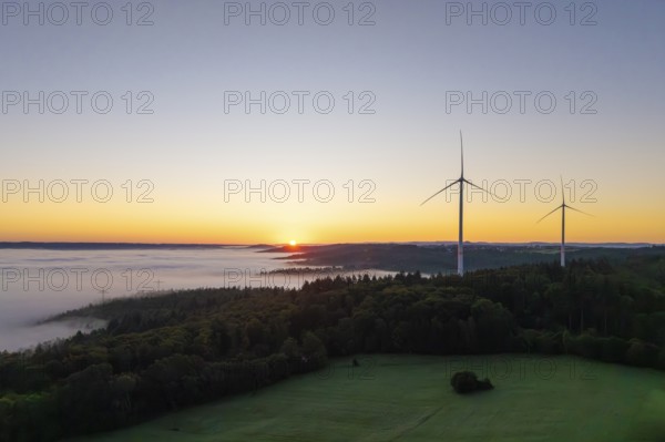 Sunrise over a foggy landscape with visible wind turbines, near Schorndorf, Remstal,