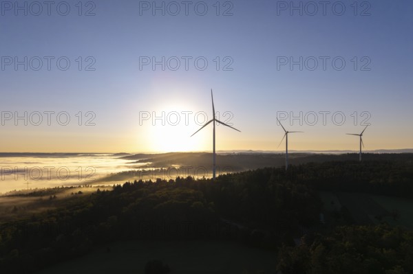 A wind turbine stands prominently in the morning fog under a clear sky, near Schorndorf, Remstal,