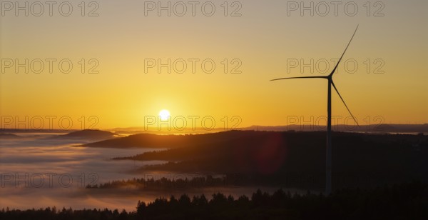 Wind turbine in front of a picturesque sunrise over a misty landscape, near Schorndorf, Remstal,