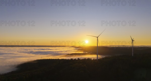 Wind turbines stand in the morning mist under a clear sunrise sky, near Schorndorf, Rems-Murr