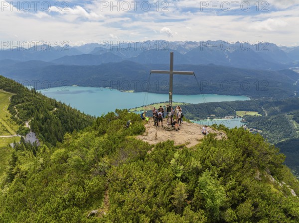 People on the summit with a cross, in the background a wide panoramic view, Herzogstand summit,