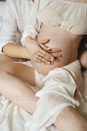 A man and woman share a tender moment as they prepare to welcome their first child. They are seated