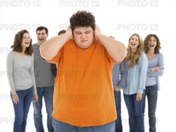 A sad boy in the foreground covers his ears while a group of teenagers laugh at him in the