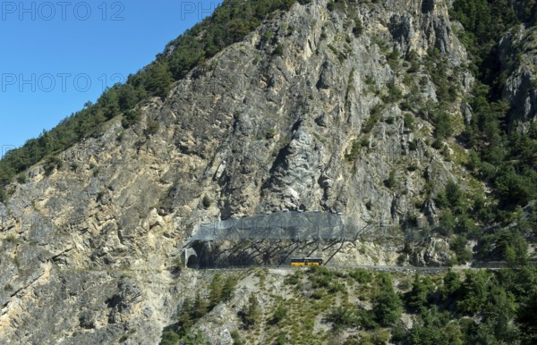 Yellow Swiss Post bus travelling under the safety nets against falling rocks to the Petits Pontis