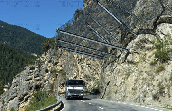 Motor vehicles travelling under safety nets on the rockfall-prone road Les Pontis, Val d'Anniviers,