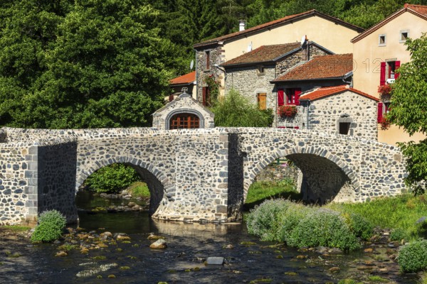 Stone bridge over the Pavin couze river flowing through the village of Saurier, Puy de Dome.