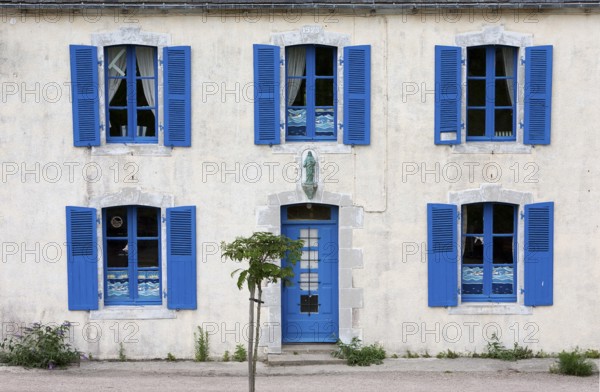 A house with blue shutters and windows, a small tree in front of it, summer atmosphere, Brittany,