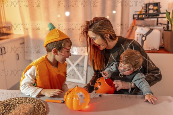 Mother and children wearing halloween costumes are sitting at a table in their kitchen, playing