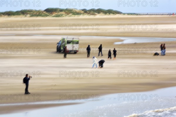 Photographer, walker on the North Sea beach, car, dunes on the horizon, wiping effect, long