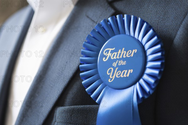 Close up of Father of the Year award ribbon pinned to man's suit chest. Celebration of fatherhood