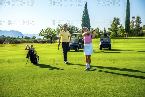 Couple enjoying a sunny day on the golf course, playing together and relishing their leisure time