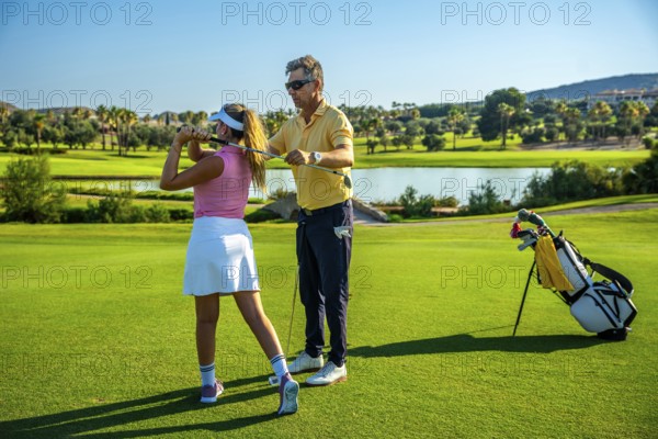 Golf instructor guiding a womans swing on a sunny golf course, showcasing technique and precision