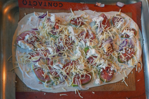 Tarte flambée with figs, onions and two types of cheese on a baking tray in the oven,