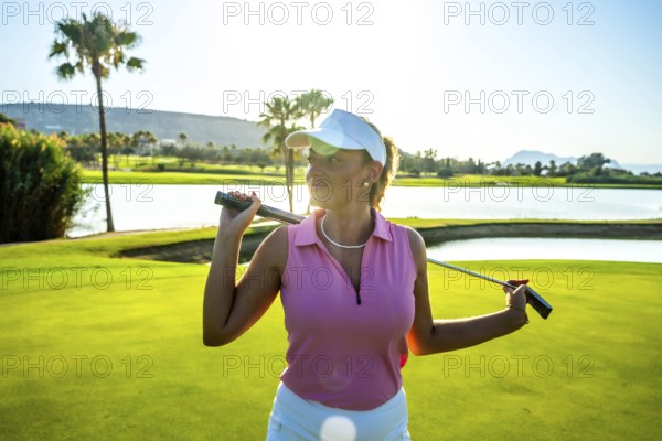 Female golfer confidently holding her golf club on her shoulders, posing gracefully on a stunning