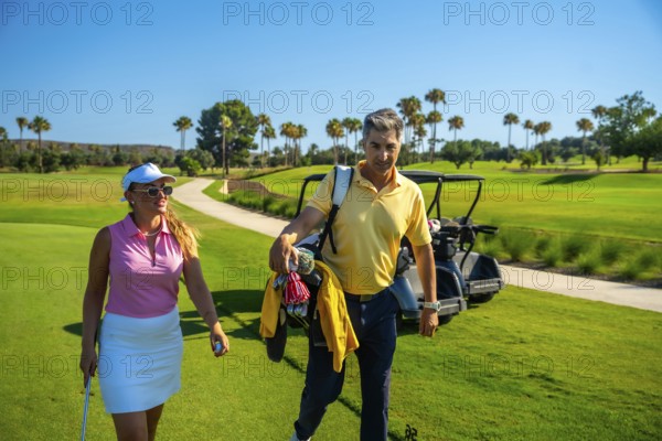 Golfers are walking on a beautiful golf course, carrying golf clubs and enjoying a sunny day of